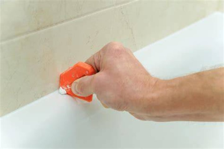 How do you remove adhesive from a bathtub?