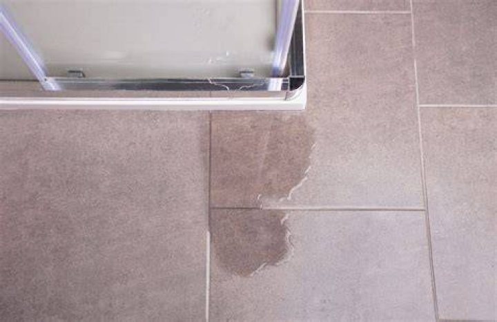 What causes a leak in a fiberglass shower base?